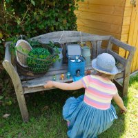 Punalu Toniebox Tasche Soundklappe ge&ouml;ffnet mit Tonies auf Gartenbank mit spielenden Kind